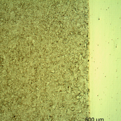 Micrography of a longitudinal section of the pipe at the interface with the clad plate, with Nital etch that reveals only the low alloy steel structure, to the left side of the image.