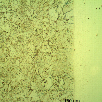 Micrography of a longitudinal section of the pipe at the interface with the clad plate, with Nital etch that reveals only the low alloy steel structure, to the left side of the image.
