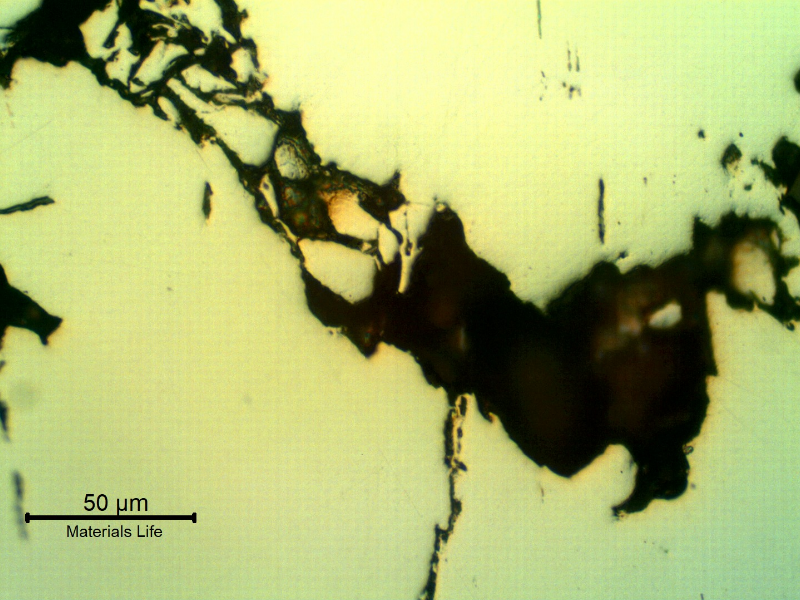 As polished micrography of the longitudinal section of the stud at the cracking transverse to the axis. It looks like inclusions/possible banding regions are contributing for the cracking and there are regions propagating witha  ductile mechanism (a network of cracks in the left side of the figure).