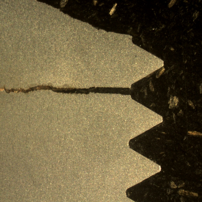 Macrography of a stud longitudinal sectiion at the fracture position (top of the figure). It is possible to see a large secondary crack at the bottom of the thread fillet adjacent to the fracture surface, without any deformation evidence.  This reveals a brittle material behavior, although the hardness measured at the stud end revealed 33HRc, as should be expected by the material specification.