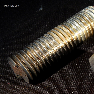 Aspect of the broken stud that was fastening a flanged line in a subsea body (tapped hole) using a nut.  The fracture, transverse to the stud axis, occurred exactly at the body to flange interface. Adjacent to the fracture, all thread fillets (positioned inside the flange hole) presented cracks at the bottom of the thread.  The stud was operating during seven years and was not corroded, indicating it was protected by the anodes.  There are also deposits in the fillets suggesting the cathodic protection was effective even inside the flange hole.