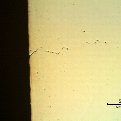 Micrography of a longitudinal section of the spring indicating that under the deposits there are intergranular cracks initiating at the spring surface.