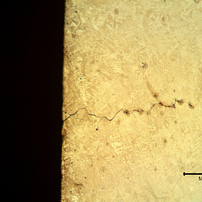 Micrographic detail of a longitudinal section of the spring indicating that under the deposits there are intergranular cracks initiating at the spring surface.