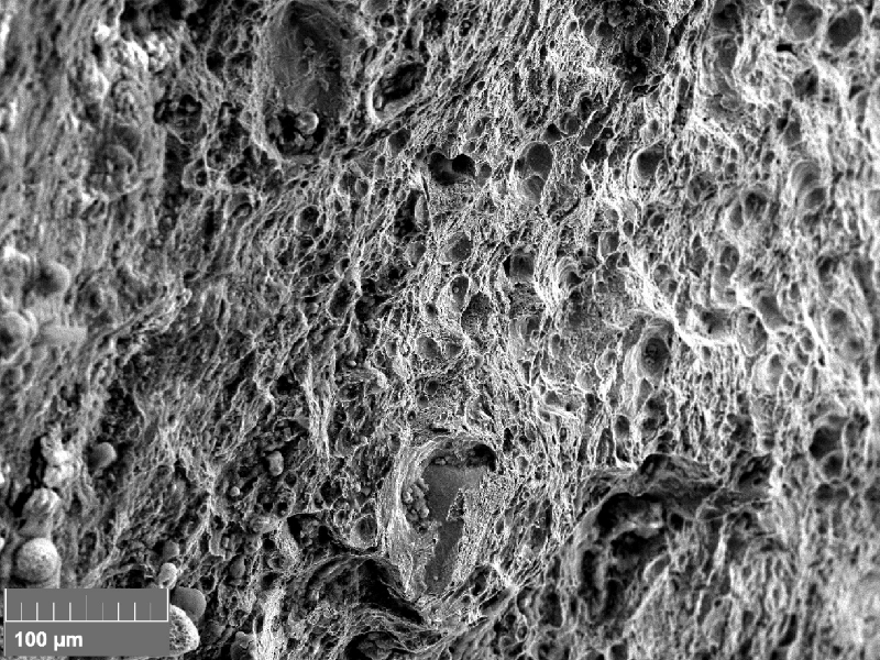 Fractographic image of the final fracture (originally 500x), presenting a ductile micromechanism by dimples.
The part was embrittled by the presence of zinc in the grain boundaries and the final fracture occurred by ductile overloading, showing that the material properties were fine out of the embrittled regions.