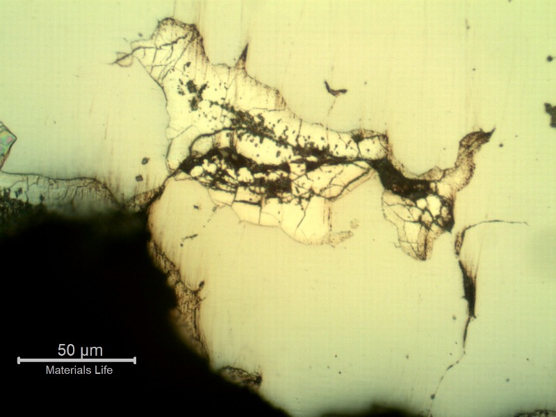 Micrographic detail of the branch cracking parallel to the fracture, as polished, showing that the cracks are filled with zinc.