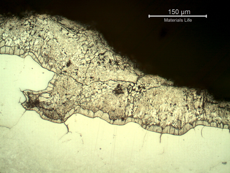 Micrographic detail of the section transverse to the fracture (top of the figure), suggesting the intergranular morphology (at the previous austenite grain boundaries) and the deposits of zinc over the fracture that create a condition of protection of the base metal during the metallographic etch, and the material is not fully etched.