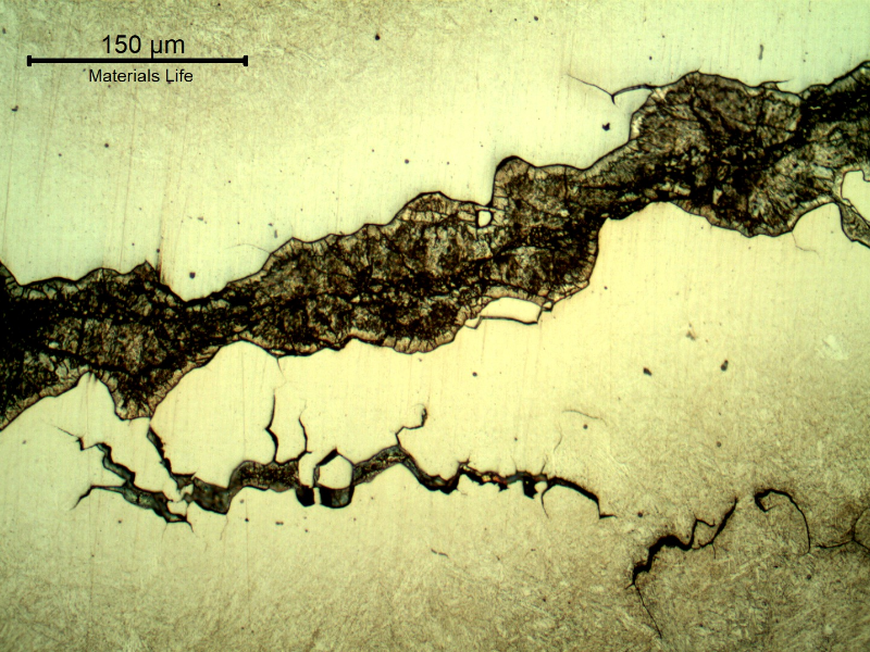Micrographic detail of the secondary intergranular cracks, filled with zinc. The zinc appears dark because of the Nital etch, and the steel is not fully revealed because of the protection by the zinc.