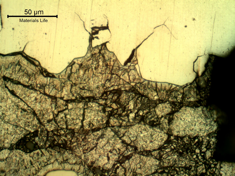 Micrographic detail of the secondary intergranular cracks, filled with zinc. The zinc appears dark because of the Nital etch, and the steel is not fully revealed because of the protection by the zinc.