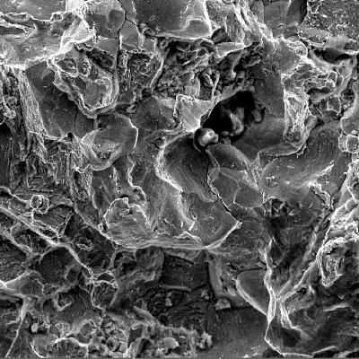 Scanning electron fractography (originally 1000x), showing intergranular aspects in the fracture surface.