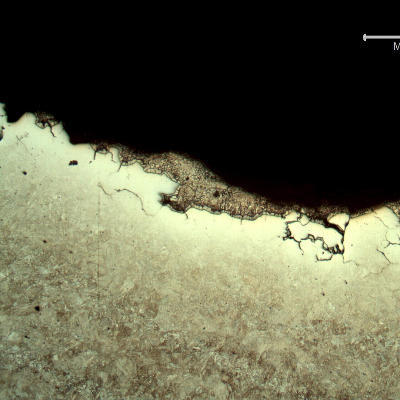 Micrography of the section transverse to the fracture (top of the figure). The fracture is intergranular, there are several secondary cracks, and there are deposits of zinc over the fracture.  The zinc makes difficult the etch with Nital to reveal the microstructure close to the fracture surface.