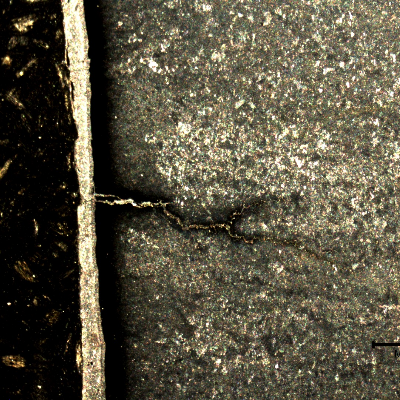 Macrographic detail of the branch cracks starting from the surface, parallel to the fracture.