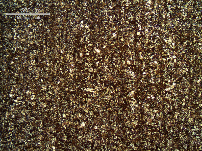 Micrography of a longitudinal section, in the center, of the broken 5/8" bolt, presenting an aged martensitic structure. There are vertical "lines" that correspond to segregation bands due to the forming direction.  These bands are evident only using low magnification microscopy.