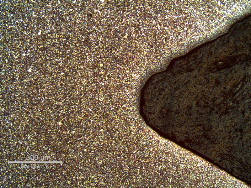 Micrography of a longitudinal section of the 5/8" bolt, at the bottom of the thread, presenting a refined structure compared to the center of the bolt and a mark at the thread flank that was probably created during tightening of the bolt.