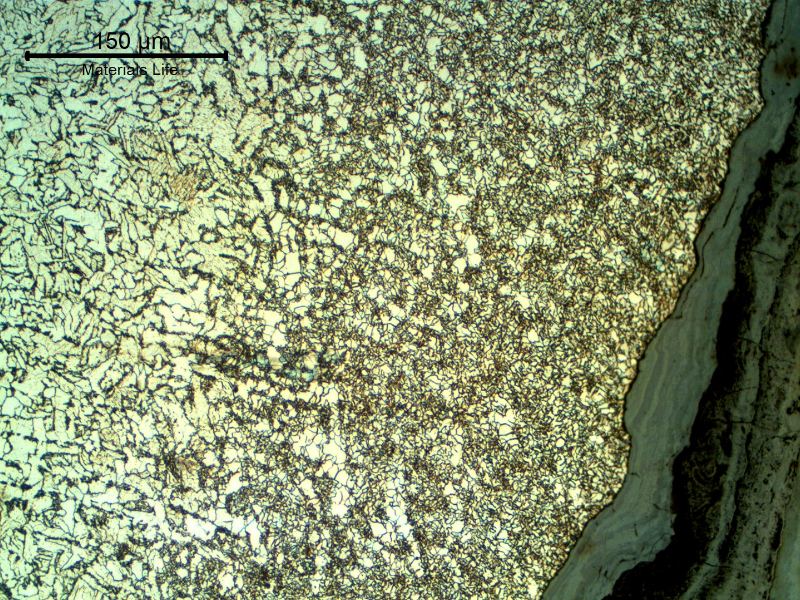 Micrography of the pipe at the leakage position showing an oxide layer inside the crevice.  The corrosion occurred exactly at the weld metal and the region at the margin of the damage shows the heat affected zone of the autogenous weld, with a refined grain size.