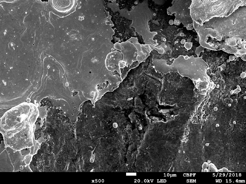 Microscopically aspect of the plate surface in the center of the bullet impact. The light and smooth surface is the melted bullet on the plate and the dark surface is the steel plate with oxides and very small surface cracks (10 microns length).