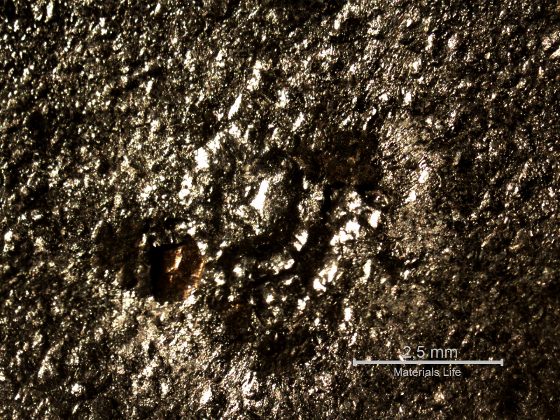Macroscopically detail of the position in the plate where the projectile strike the plate. No damage of the plate but foreign material (from the bullet) adhered at the surface.