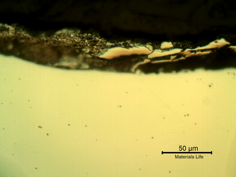 Micrographic detail of the plate section, as polished, close to the surface that suffered the impact.  The deposits at the surface are the melted bullet films.