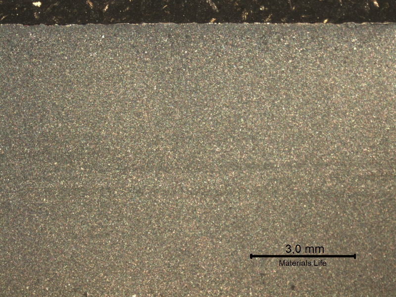Macrography of the plate section, presenting the impact surface in the top of the figure. It is possible to see the lines with a gradient in the etch that characterizes the segregations (light) in the center of the plate.