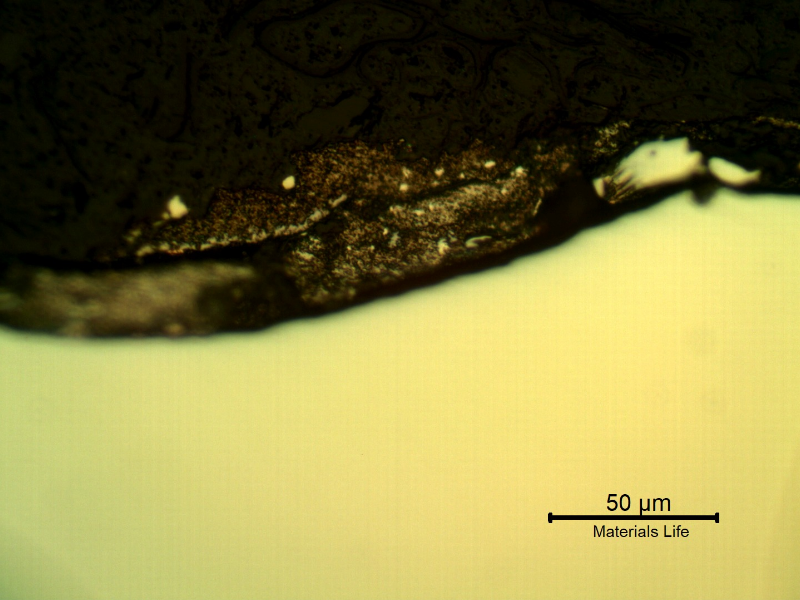 Micrographic detail of the plate section, as polished, close to the surface that suffered the impact. The lead alloy melted and formed this gray deposit.