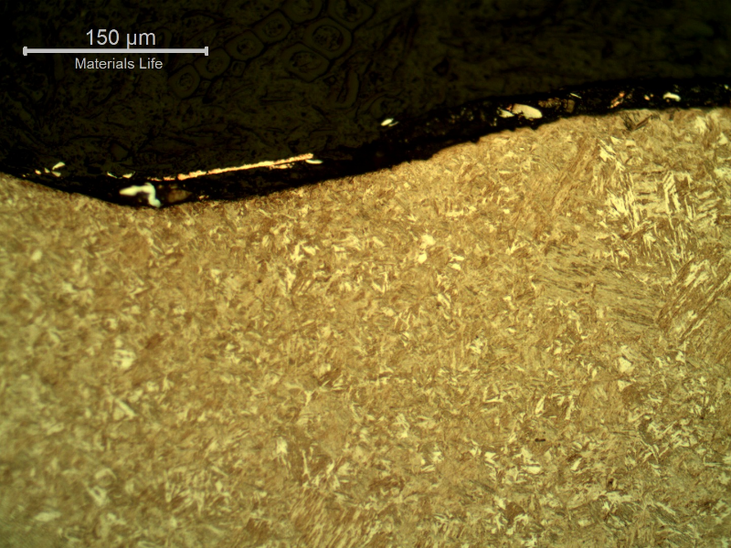 Micrography of the plate section, close to the surface that suffered the impact.  After etching the film at the surface does not appear very well.  Again it is possible to see the smooth waves but no evidences of damage in the plate microstructure.