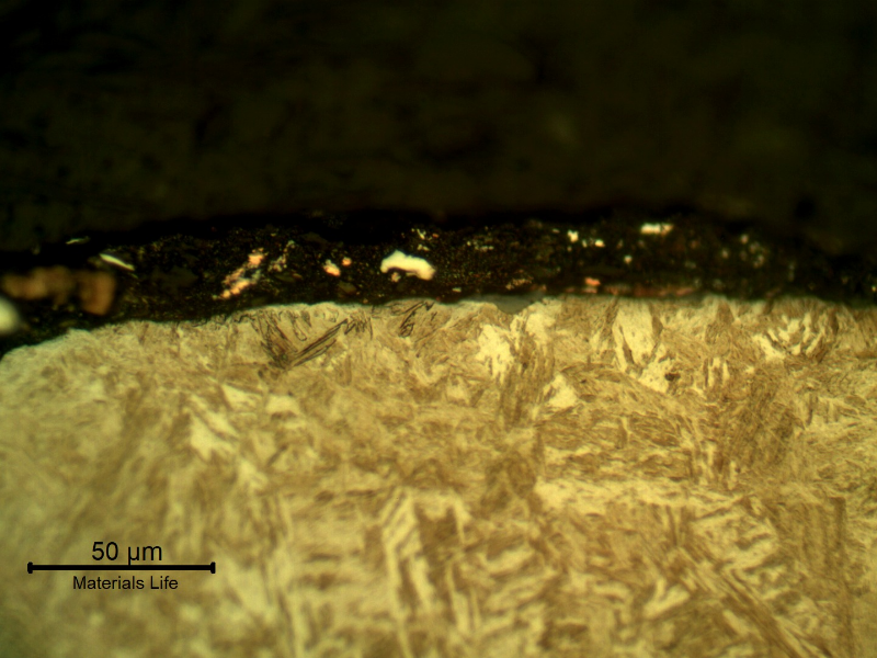 Micrographic detail of the plate section, close to the surface that suffered the impact.  After etching the lead alloy film at the surface appears dark gray and the copper alloy film appears clear and orange.  There are small oxides at the film to plate interface (probably entrapped) but no damage in the plate microstructure.