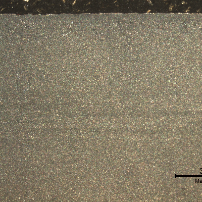 Macrography of the plate section, presenting the impact surface in the top of the figure.  It is possible to see the lines with a gradient in the etch that characterizes the segregations (light) in the center of the plate.