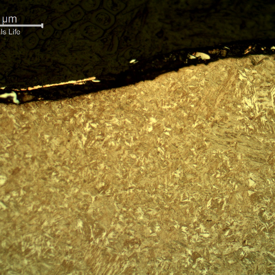 Micrography of the plate section, close to the surface that suffered the impact.  After etching the film at the surface does not appear very well.  Again it is possible to see the smooth waves but no evidences of damage in the plate microstructure.