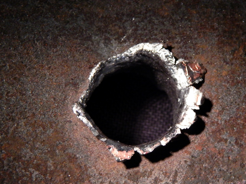 Detail of the position where the projectile strike the plate. The plate suffered a localized perforation.