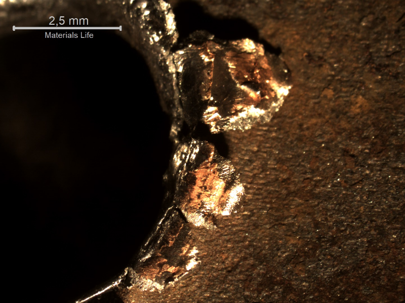 Detail of the margin of the perforated hole in the impact position. It is interesting to observe that the perforation caused the material to be expulsed from the hole, in the direction of the impact.