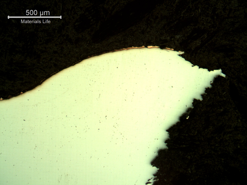 Micrographic detail of the plate section, as polished, close to the surface that suffered the impact. The plate material deformed during the perforation,