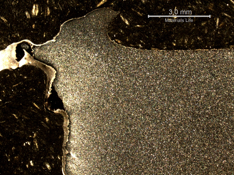 Macrographic detail of the 3/8" low carbon steel plate.  The side of bullet impact is to the top of the figure. The perforated hole expulsed the material to the top and bottom directions. The hole is in the left side of the figure.
