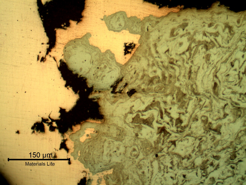 Micrography of the damaged plate at the side of the bullet impact, top of the figure. The perforated hole expulsed the material to the top and bottom directions and the copper alloy is evident at the hole surface.After etching it is clear the strong plastic deformation of the plate microstructure.