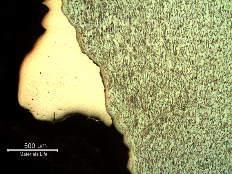 Micrography of the damaged plate inside the hole, showing the strong plastic deformation of the ferritic-pearlitic structure and the copper alloy adhered at the hole surface.