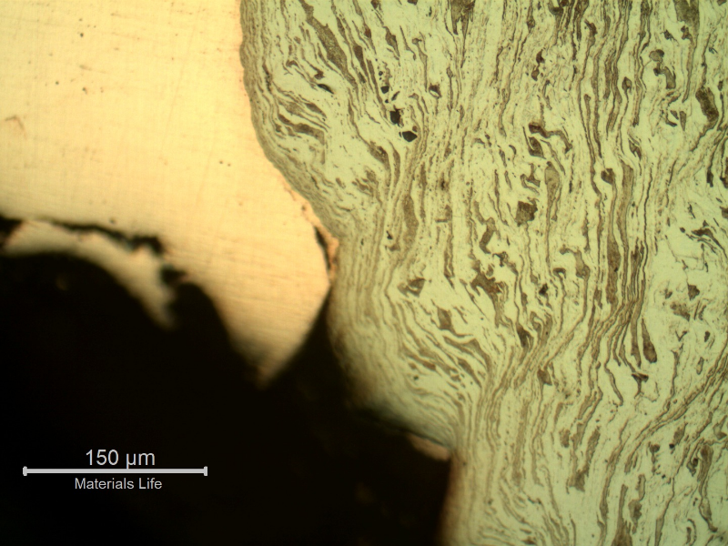 Micrographic detail of the strong plastic deformation of the ferritic-pearlitic structure and the copper alloy adhered at the hole surface.