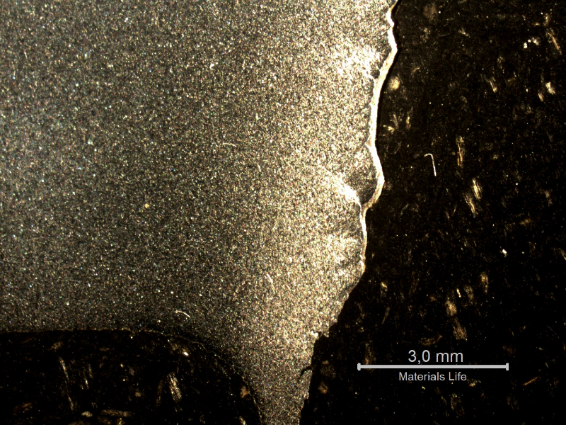 Macrographic detail of the 3/8" thickness low carbon steel plate. The side of bullet exit is to the bottom of the figure. The perforated hole expulsed the material to the top and bottom directions. The hole is in the right side of the figure.