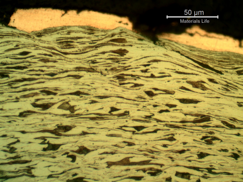 Micrographic detail of the copper alloy melted and adhered at the surface and a strong plastic deformation of the plate microstructure.