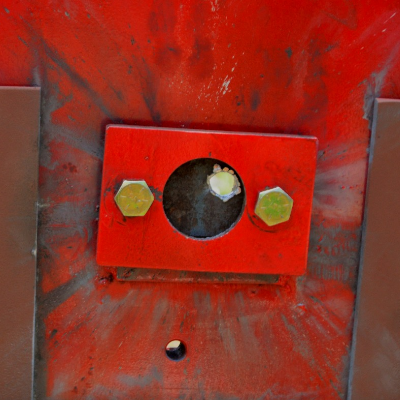 Red painted device where the 50 mm x 50 mm carbon steel plate was positioned (in the circle). The image presents the target, positioned 100 meters far from the gun, after the shot and the projectile perforated the plate, as will be presented in the other figures.