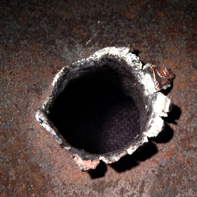 Detail of the position where the projectile strike the plate. The plate suffered a localized perforation.