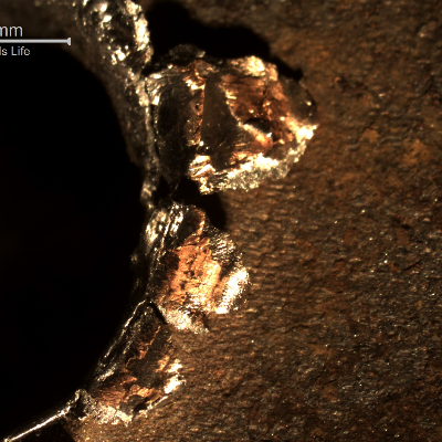 Detail of the margin of the perforated hole in the impact position.  It is interesting to observe that the perforation caused the material to be expulsed from the hole, in the direction of the impact.
