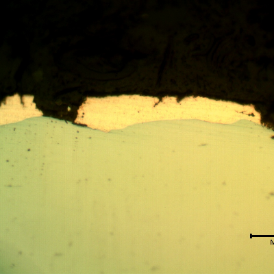Micrographic detail of the plate section, as polished, close to the surface that suffered the impact. The copper alloy melted and created  a yellow-orange deposit.