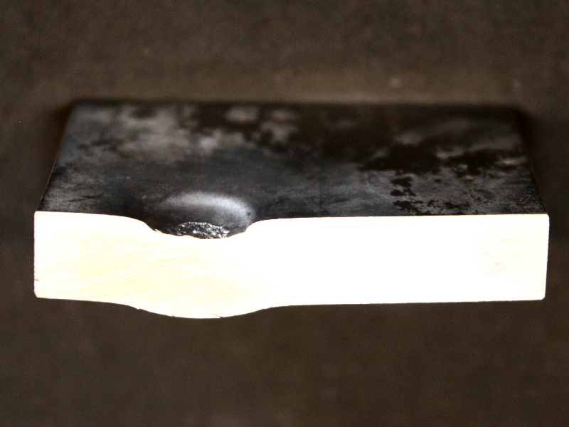 Aspect of the 3/8" thickness plate, 50 mm x 50 mm, of the titanium alloy, in a section transverse to the impact position that is to the top of the figure. The projectile did not perforate the plate but caused a localized plastic deformation and a shear effect.