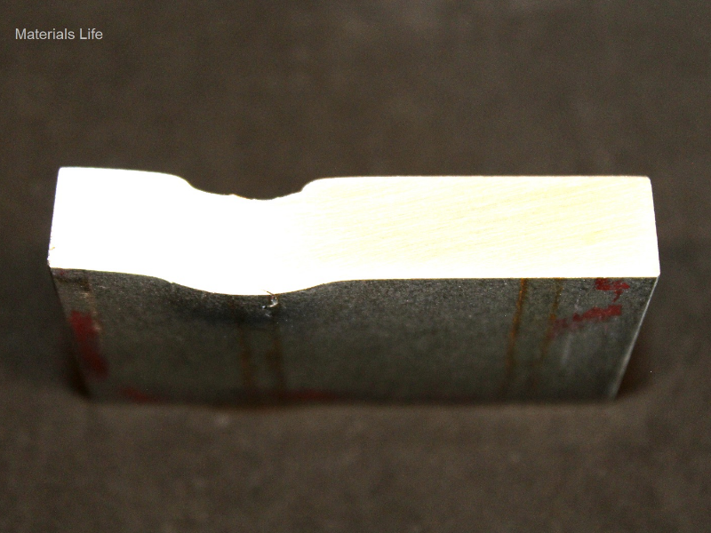Aspect of the 3/8" thickness plate, 50 mm x 50 mm, of the titanium alloy, in a section transverse to the impact position that is to the top of the figure. The projectile did not perforate the plate but caused a localized plastic deformation and cracks that appear in the opposite site of the plate at the projectile impact position.