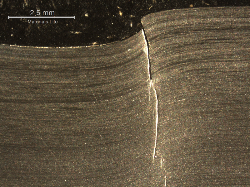 Macrography of the 3/8" thickness titanium alloy plate, in a section. The impact side of the plate is to the top of the figure. The plate was sheared through wall in a very localized position. HF+HNO3+H2O chemical etch.