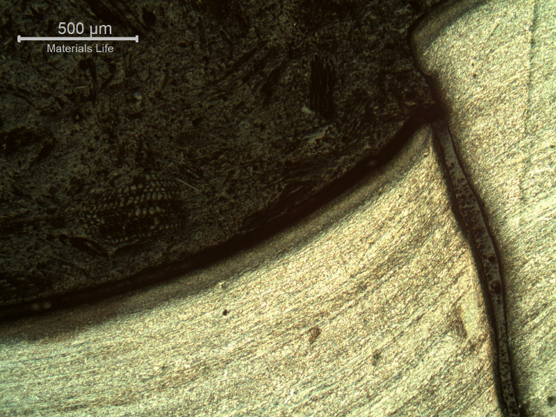 Micrography of the damaged plate at the side of the bullet impact, top of the figure. The projectile sheared the plate but did not perforate it, and the projectile materials (Cu and Pb) deposited at the .surface.   HF+HNO3+H2O chemical etch.