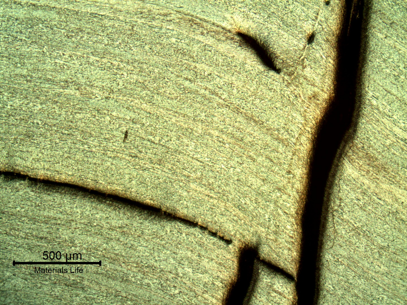 Micrography of the damaged plate at the side of the bullet impact, top of the figure. The projectile, impacted in the right side of the crack, sheared the plate but did not perforate it and created several longitudinal ductile secondary cracks.  HF+HNO3+H2O chemical etch.