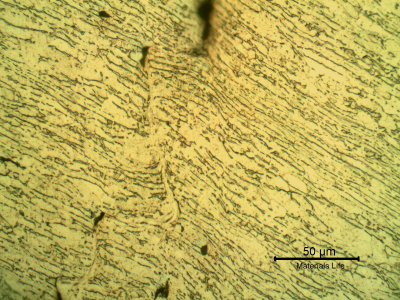 Micrographic detail of the shearing of the material due to the projectile impact.  It is a very localized effect.  HF+HNO3+H2O chemical etch.