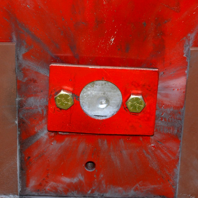 Red painted device where the 50 mm x 50 mm titanium alloy plate was positioned (in the circle). The image presents the target, positioned 100 meters far from the gun, after the shot and the projectile did not perforate the plate, but presented a strong effect, as will be presented in the other figures.