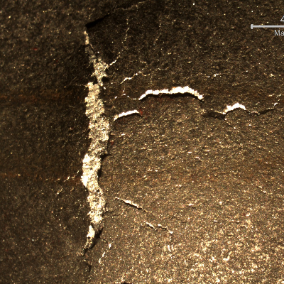 Detail of the position observed form the back side of the plate, where the projectile deformed the plate and cracked it.