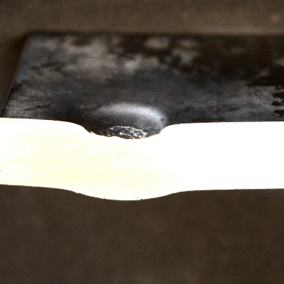 Aspect of the 3/8" thickness plate, 50 mm x 50 mm, of the titanium alloy, in a section transverse to the impact position that is to the top of the figure. The projectile did not perforate the plate but caused a localized plastic deformation and a shear effect.