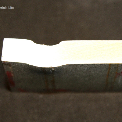 Aspect of the 3/8" thickness plate, 50 mm x 50 mm, of the titanium alloy, in a section transverse to the impact position that is to the top of the figure. The projectile did not perforate the plate but caused a localized plastic deformation and cracks that appear in the opposite site of the plate at the projectile impact position.